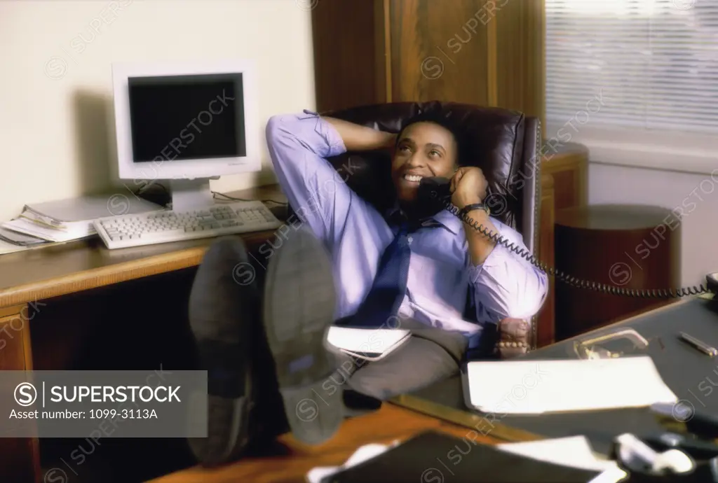 High angle view of a businessman sitting in an office talking on the telephone