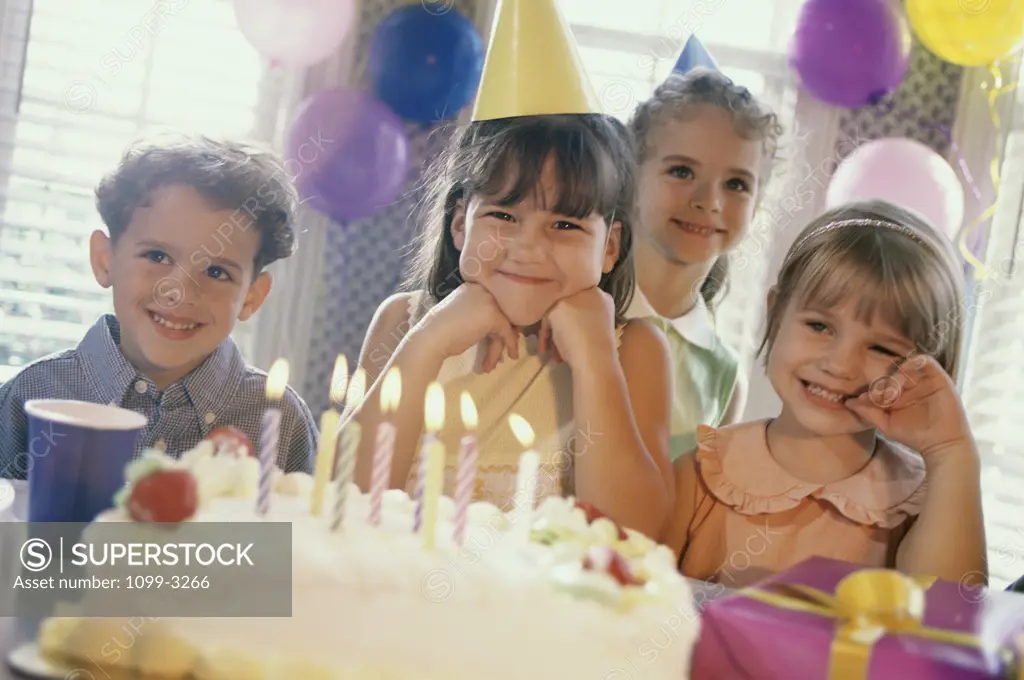 Portrait of a group of children in front of a birthday cake at a birthday party