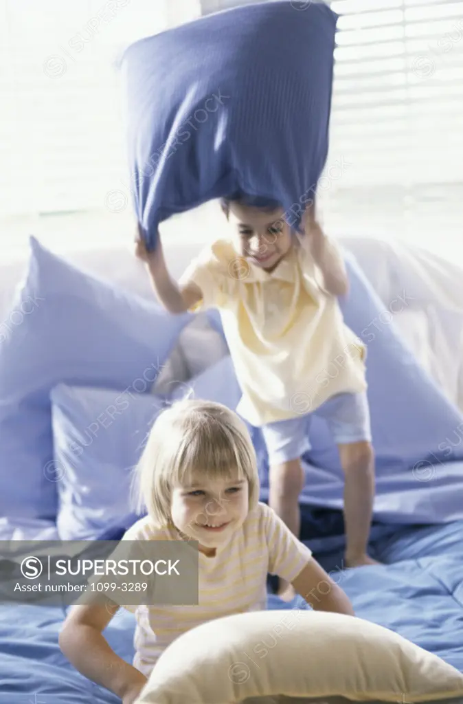Brother and sister having a pillow fight