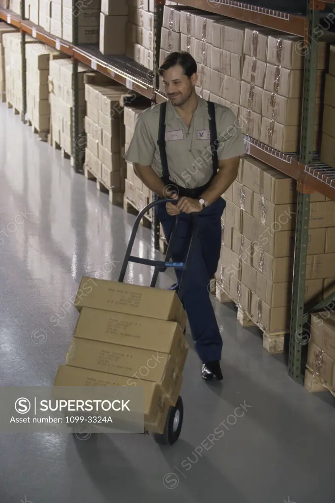 High angle view of a mid adult man pushing a trolley in a warehouse