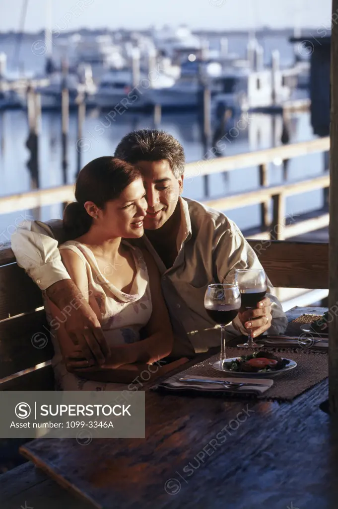 Young couple sitting by a harbor and having food