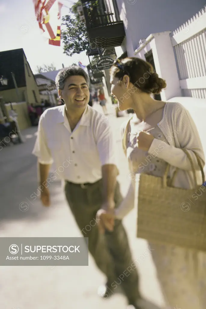 Young couple walking on the sidewalk holding hands