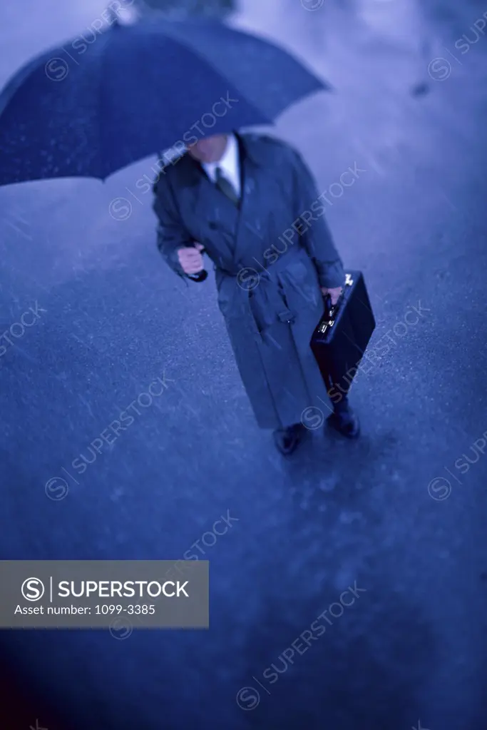 High angle view of a businessman holding an umbrella and a briefcase