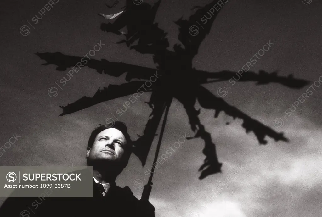 Low angle view of a businessman standing under a broken umbrella
