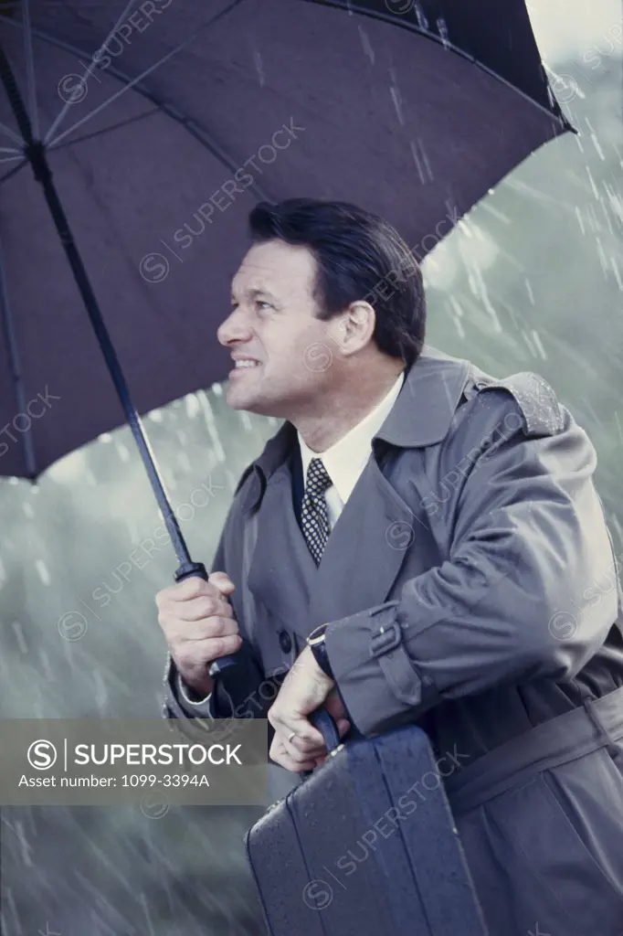 Businessman holding a briefcase and an umbrella in the rain