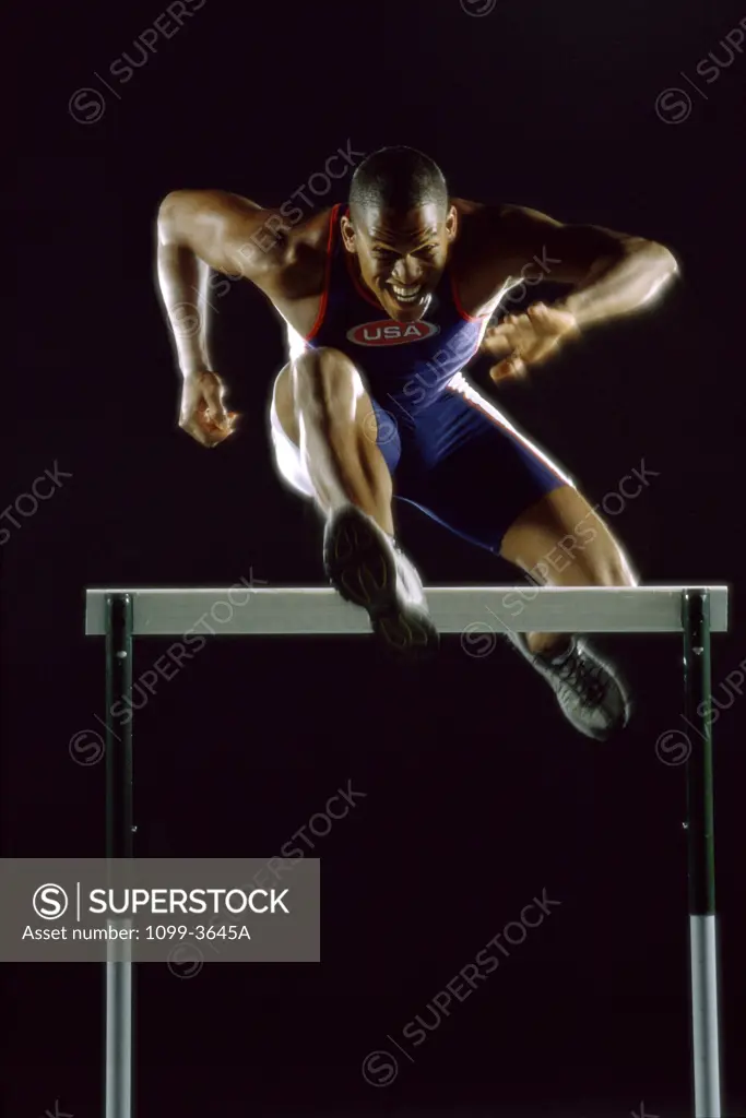 Portrait of a young man jumping over a hurdle