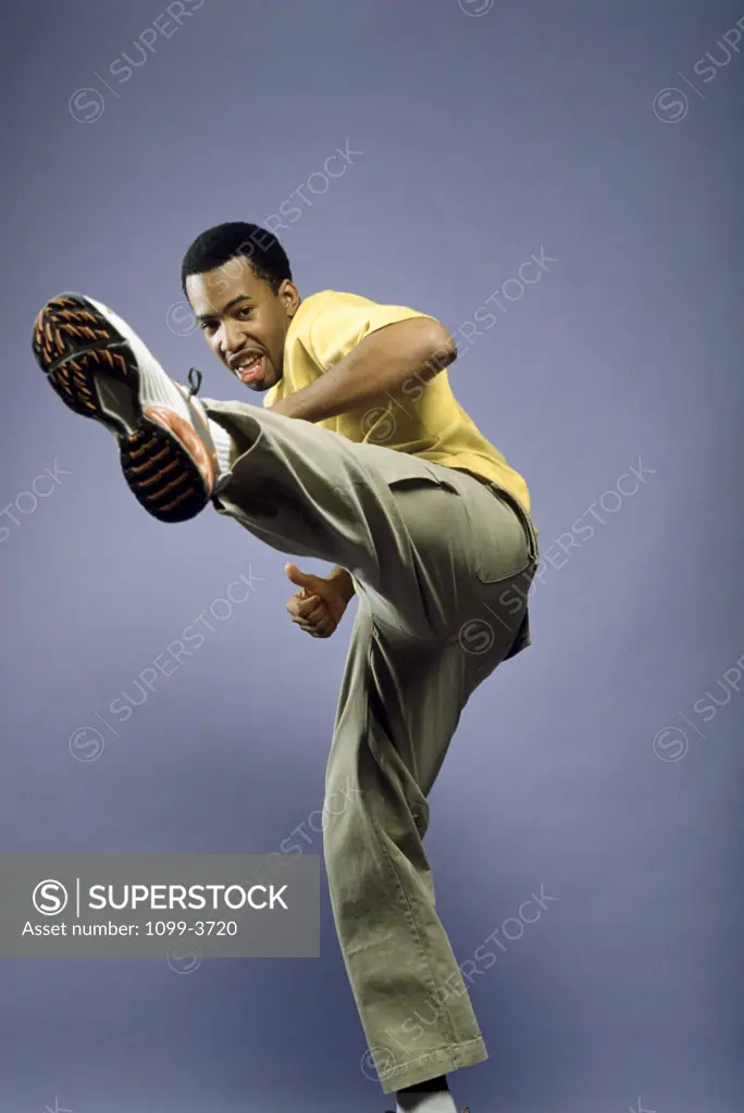 Side profile of a young man kicking