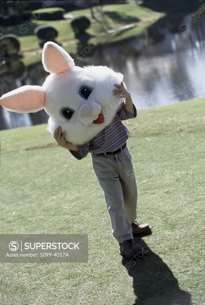 Boy holding an Easter Bunny mask in a garden