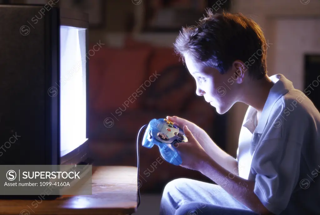 Side profile of a teenage boy playing video games