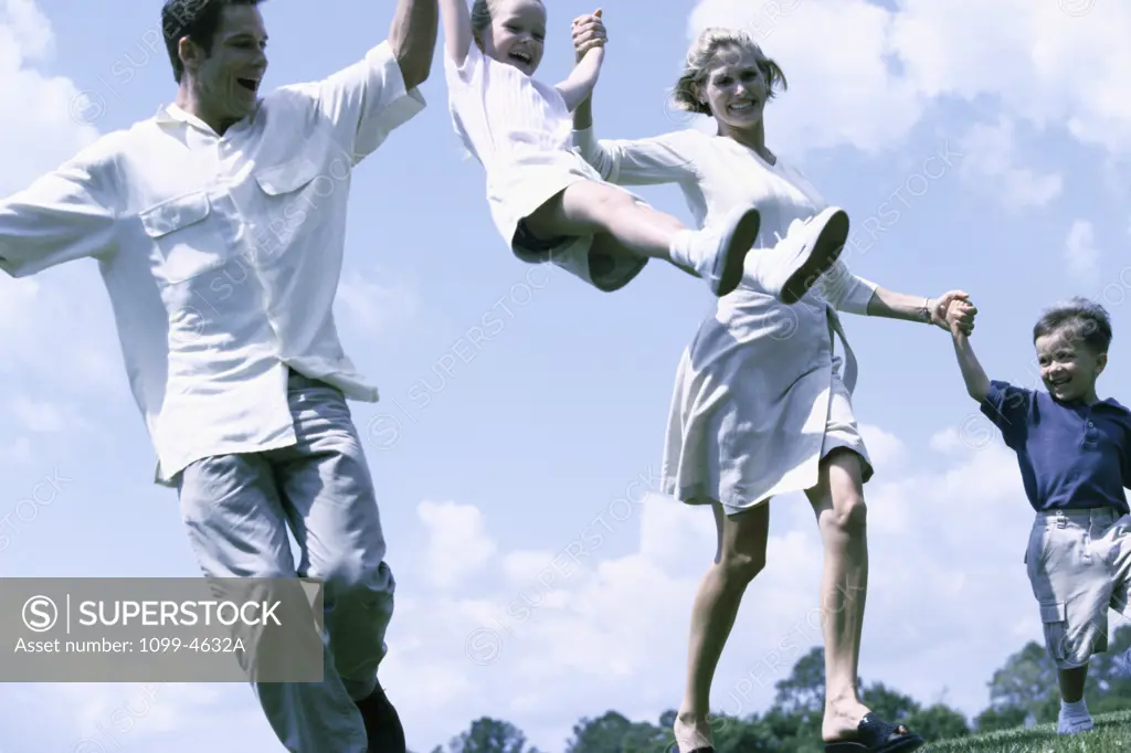 Low angle view of parents swinging their daughter