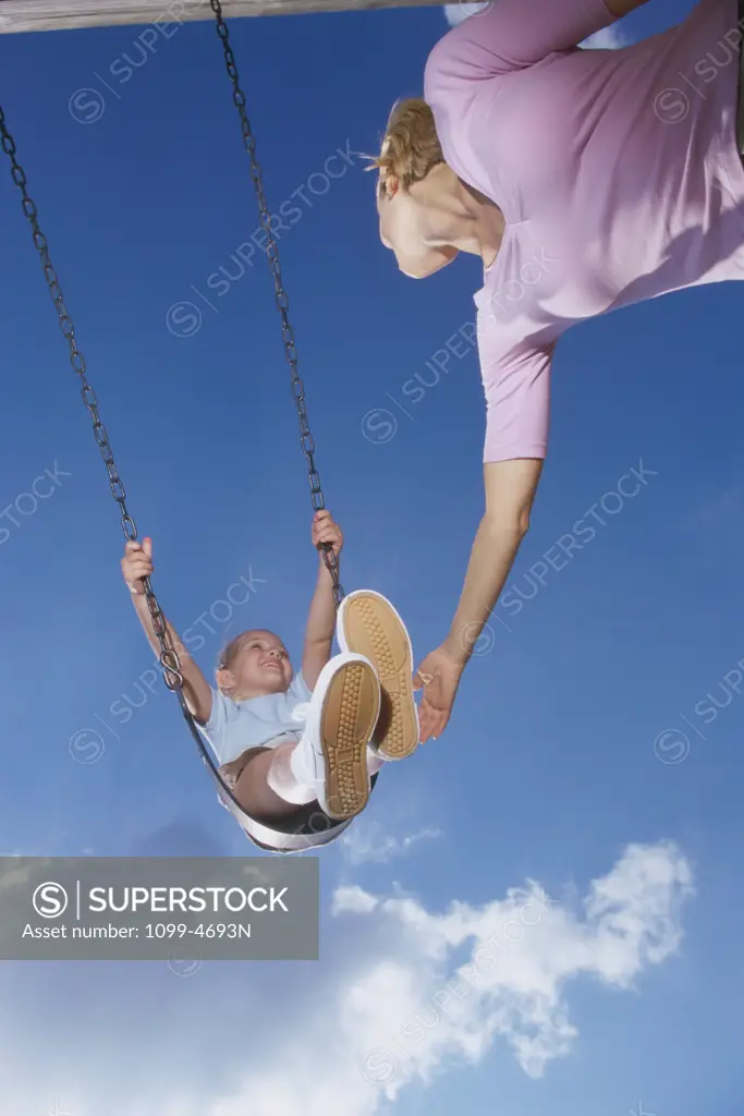 Low angle view of a mother pushing her daughter on a swing