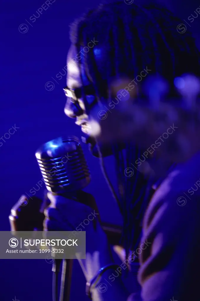 Side profile of a young man singing into a microphone