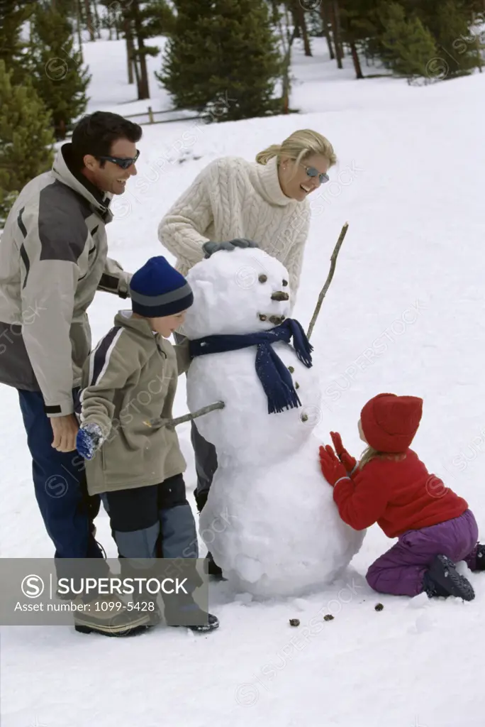 Parents standing with their son and daughter around a snowman
