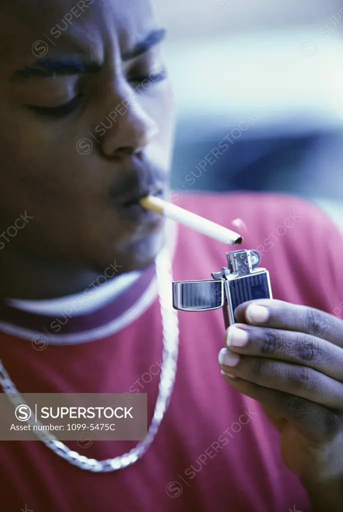 Close-up of a teenage boy lighting a cigarette
