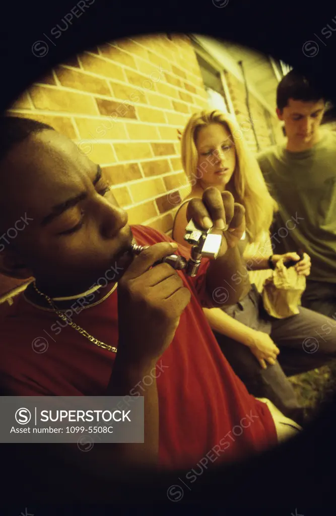 Side profile of a group of teenagers smoking opium in a pipe