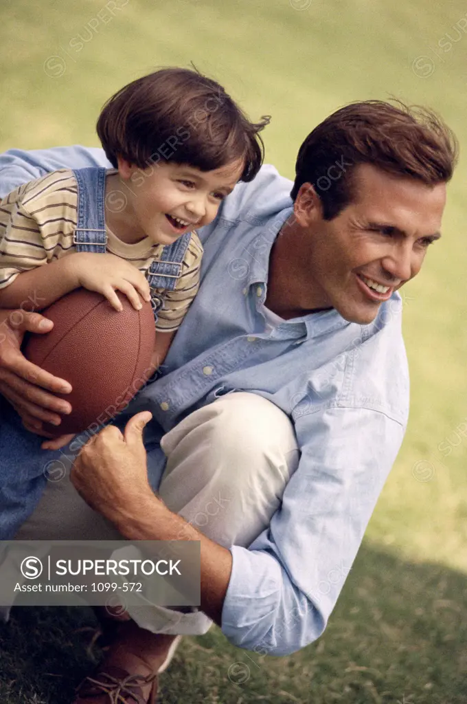 Father holding his daughter and a football