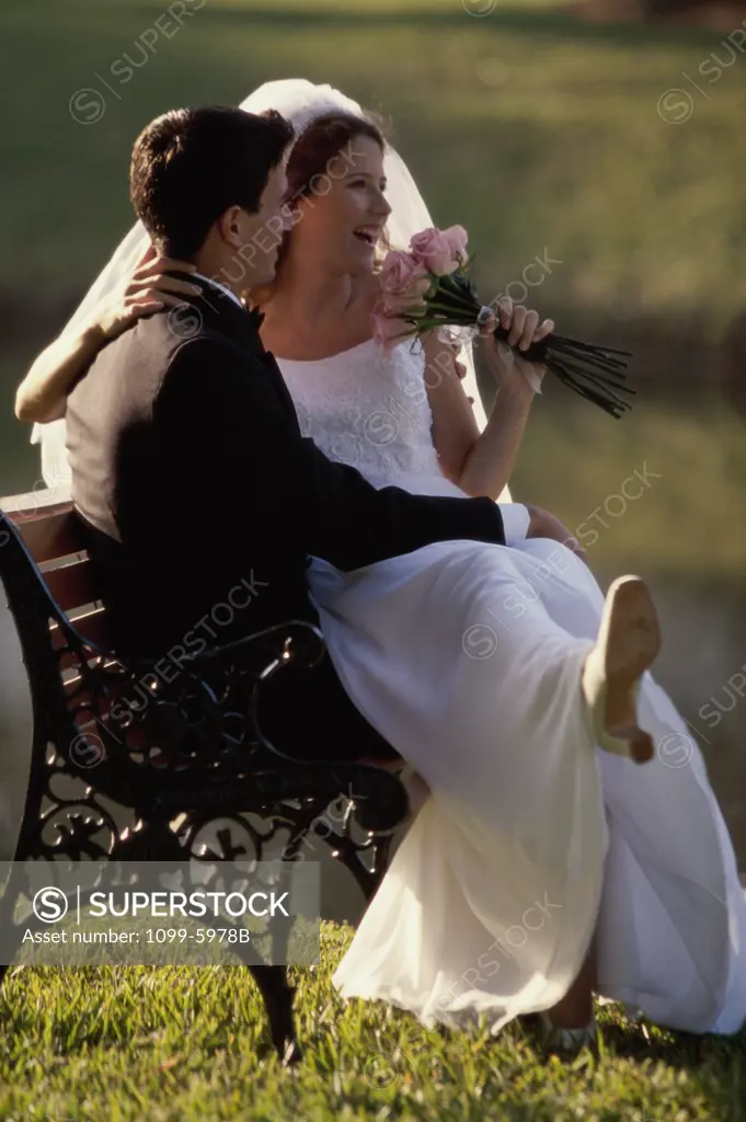 Newlywed couple sitting on a park bench
