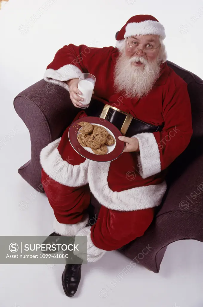 Portrait of Santa Claus holding a glass of milk and a plate of cookies