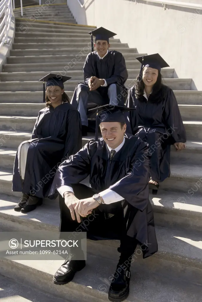 Portrait of four young graduates sitting on stairs