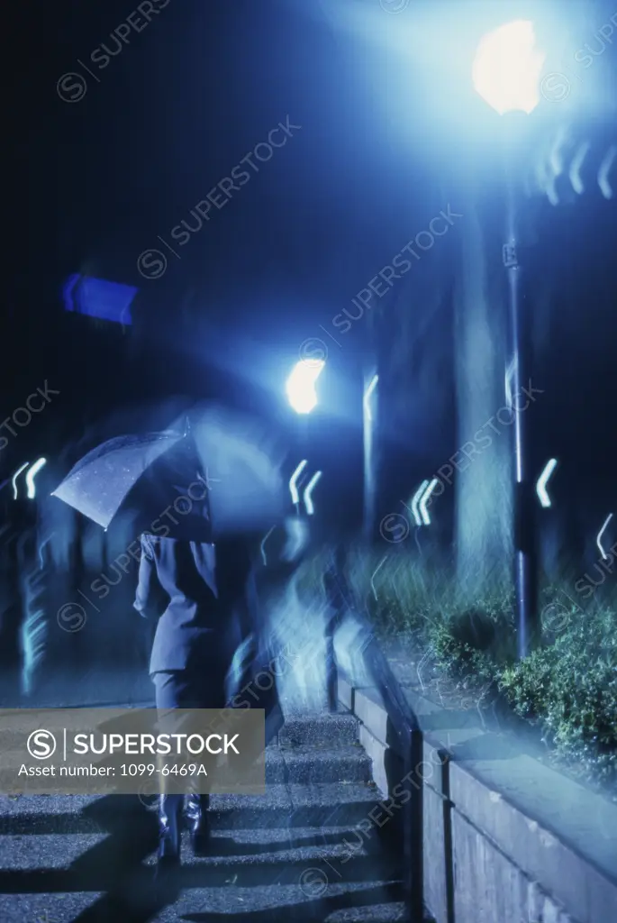 Rear view of a businesswoman holding an umbrella in the rain