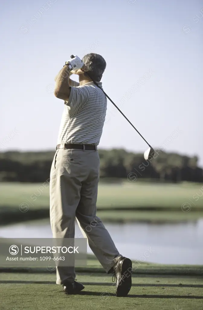 Rear view of a senior man swinging a golf club