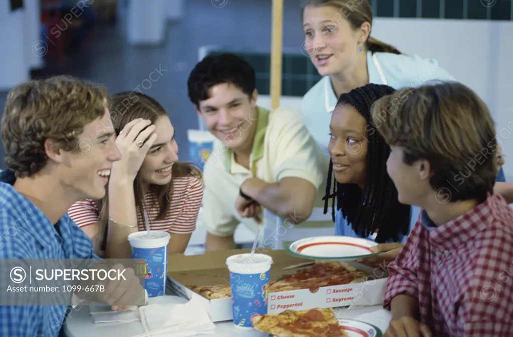 Group of teenagers eating pizza in a restaurant