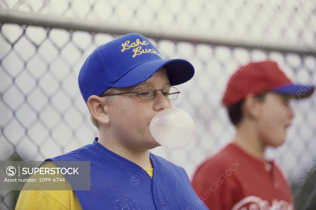 Two boys on a baseball team blowing bubble gum