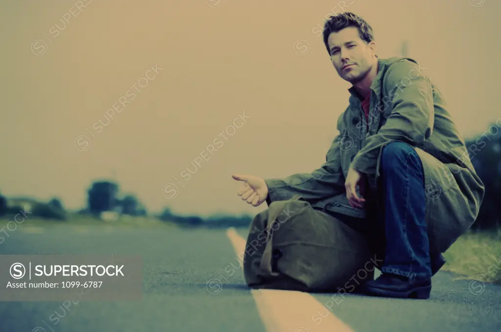 Side profile of a young man crouching on the side of the road