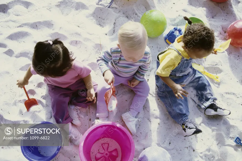 High angle view of a girl and two boys playing in the sand