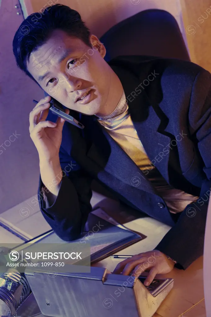 Portrait of a businessman talking on a mobile phone and using a calculator