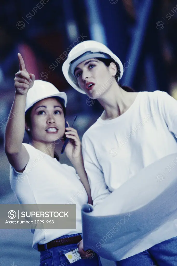 Two female construction workers pointing at a construction site