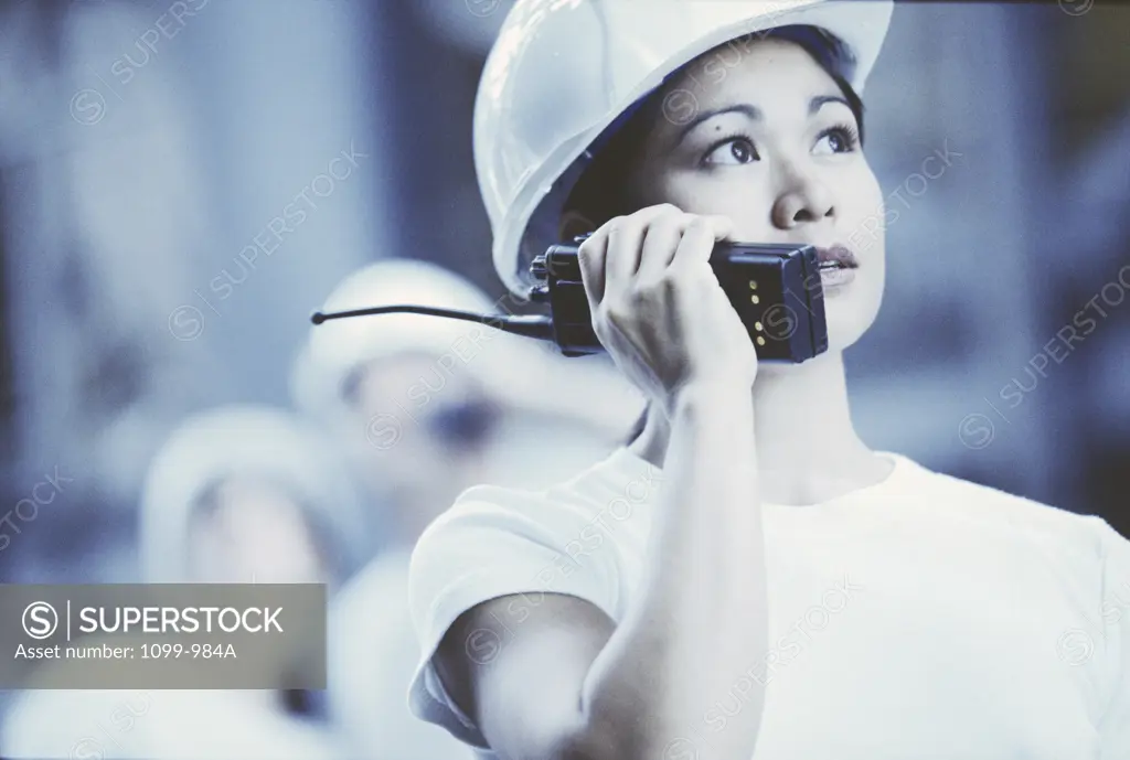 Female construction worker talking on a walkie-talkie looking up