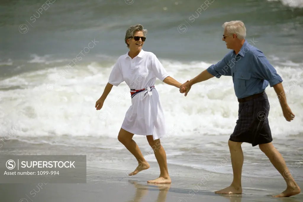 Senior couple holding hands on the beach