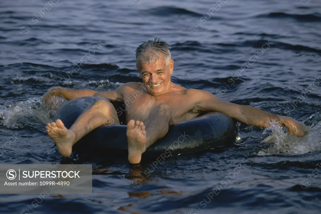 Portrait of a senior man floating on an inner tube