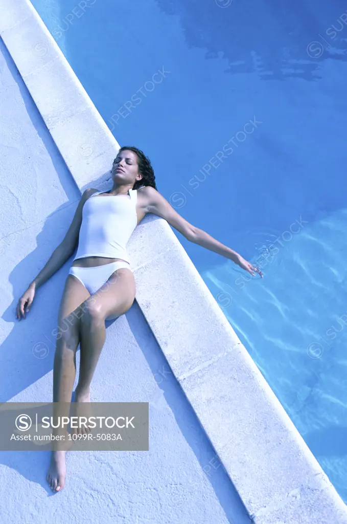 High angle view of a young woman lying near a swimming pool