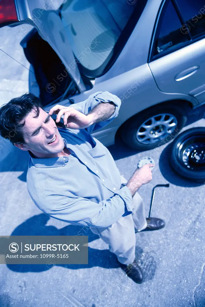 Man talking on a mobile phone near a car