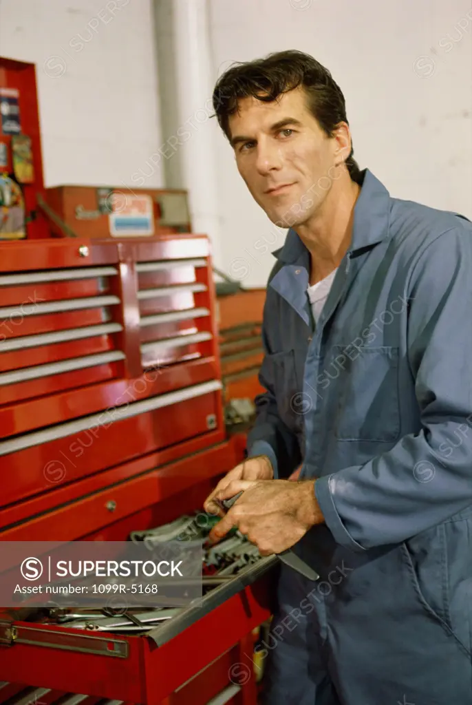 Portrait of a auto mechanic standing at a toolbox in a garage