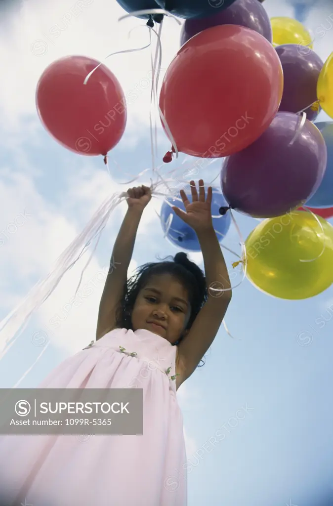 Low angle view of a girl holding balloons