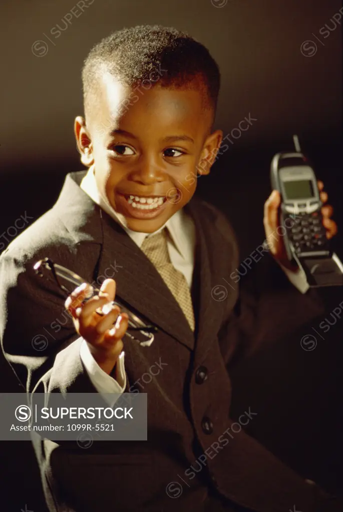 Young boy dressed as a businessman holding two mobile phones