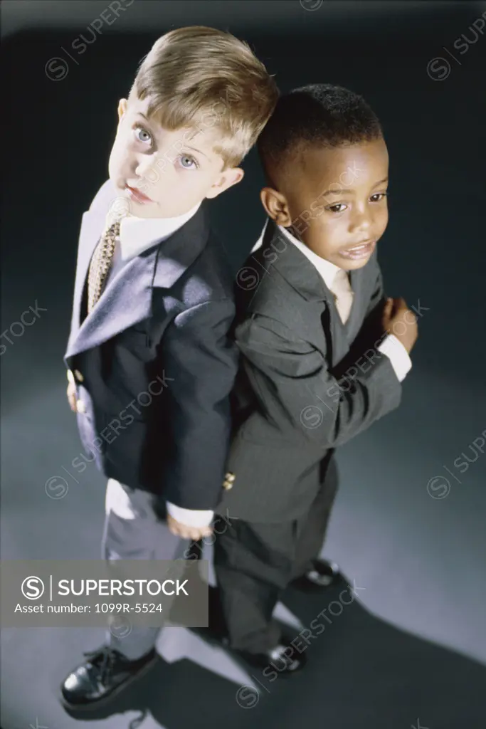 High angle view of two young boys dressed as businessmen standing back to back