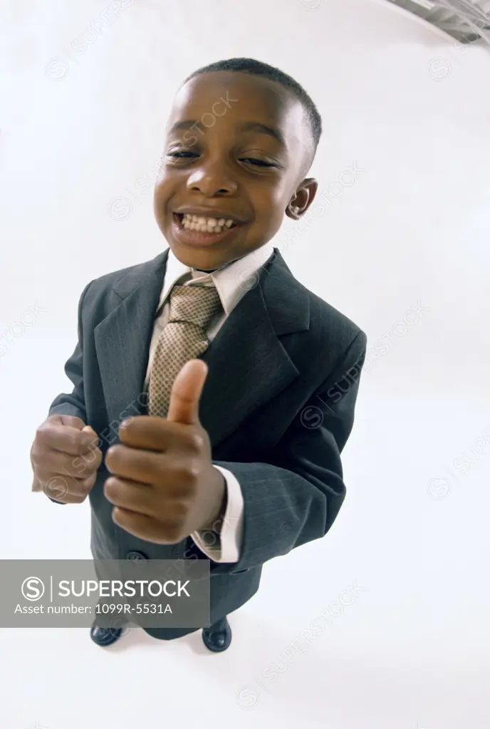 Portrait of a young boy dressed as a businessman gesturing thumbs up