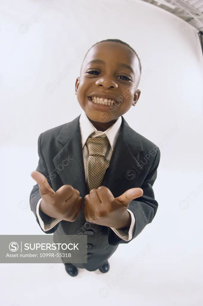 Portrait of a young boy dressed as a businessman gesturing thumbs up smiling