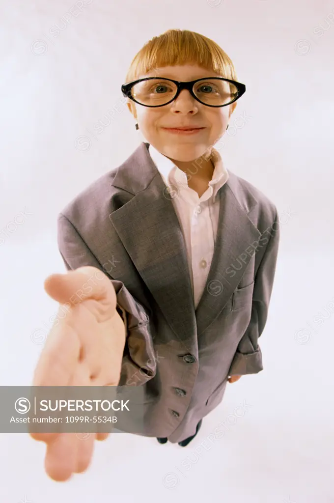 Portrait of a young boy dressed as a businessman holding his hand out smiling