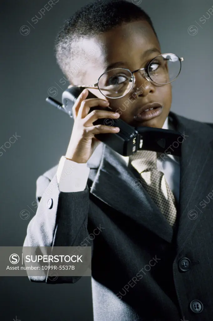 Young boy dressed as a businessman talking on a mobile phone