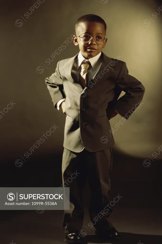 Portrait of a young boy dressed as a businessman standing with his hands on his hips