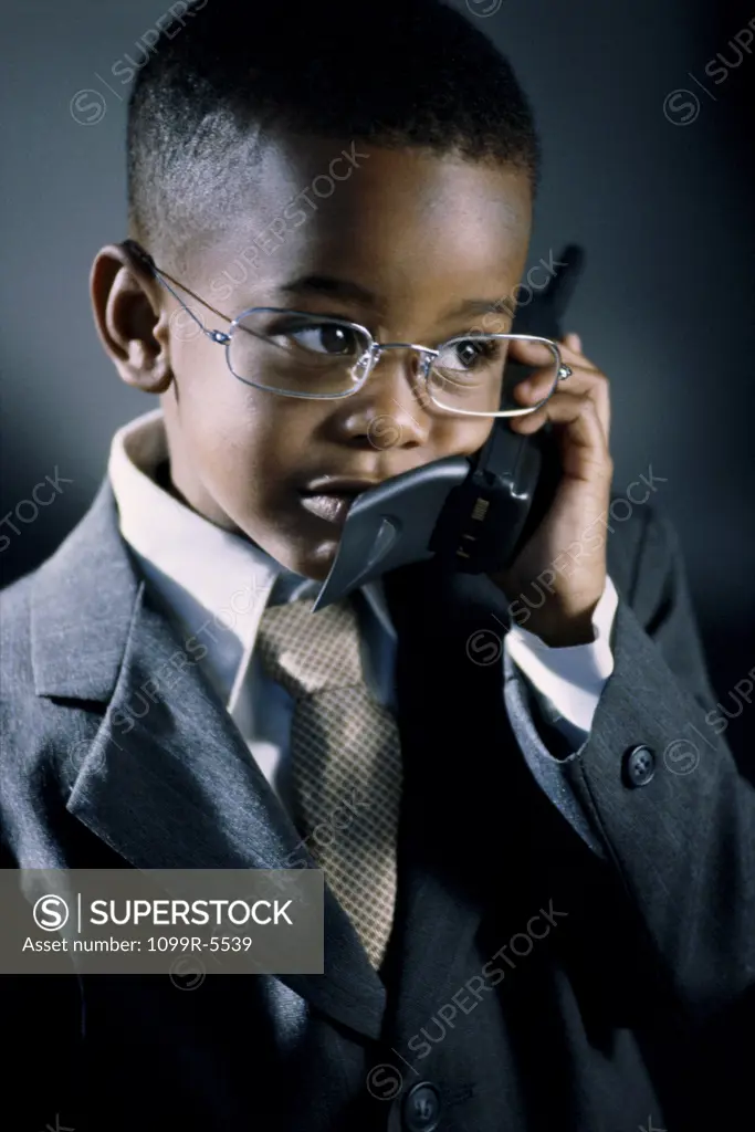 Young boy dressed as a businessman talking on a mobile phone