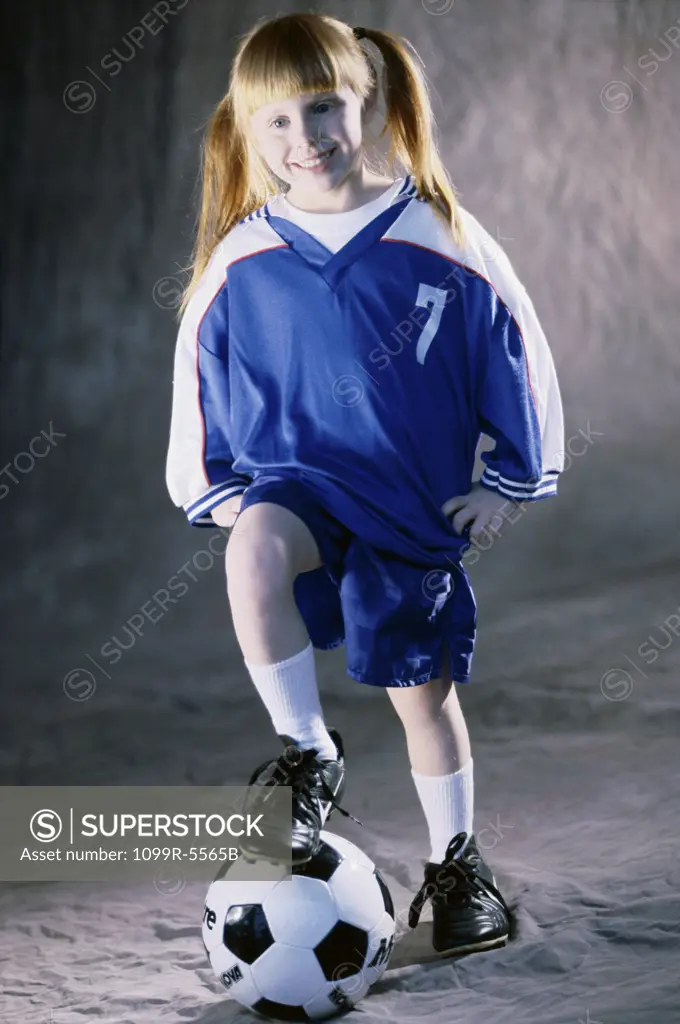 Portrait of a girl standing with her foot on a soccer ball