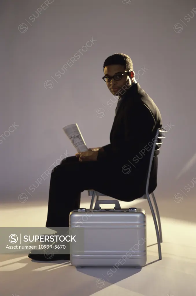 Businessman sitting on a chair holding a newspaper