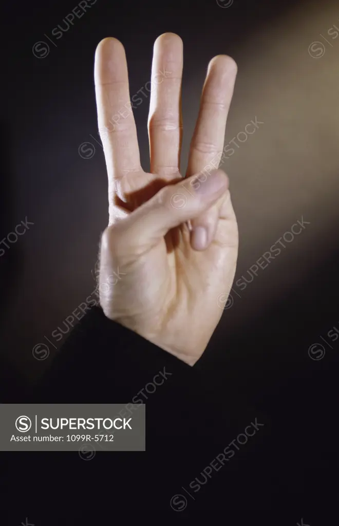 Close-up of a person's hand holding out three fingers