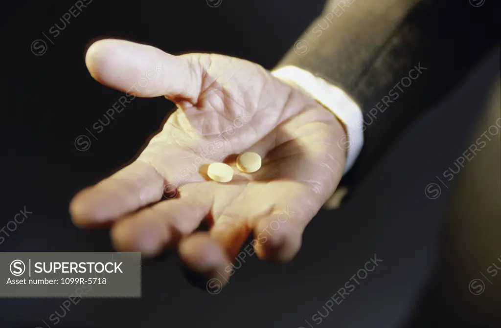 Close-up of a person's hand holding two pills